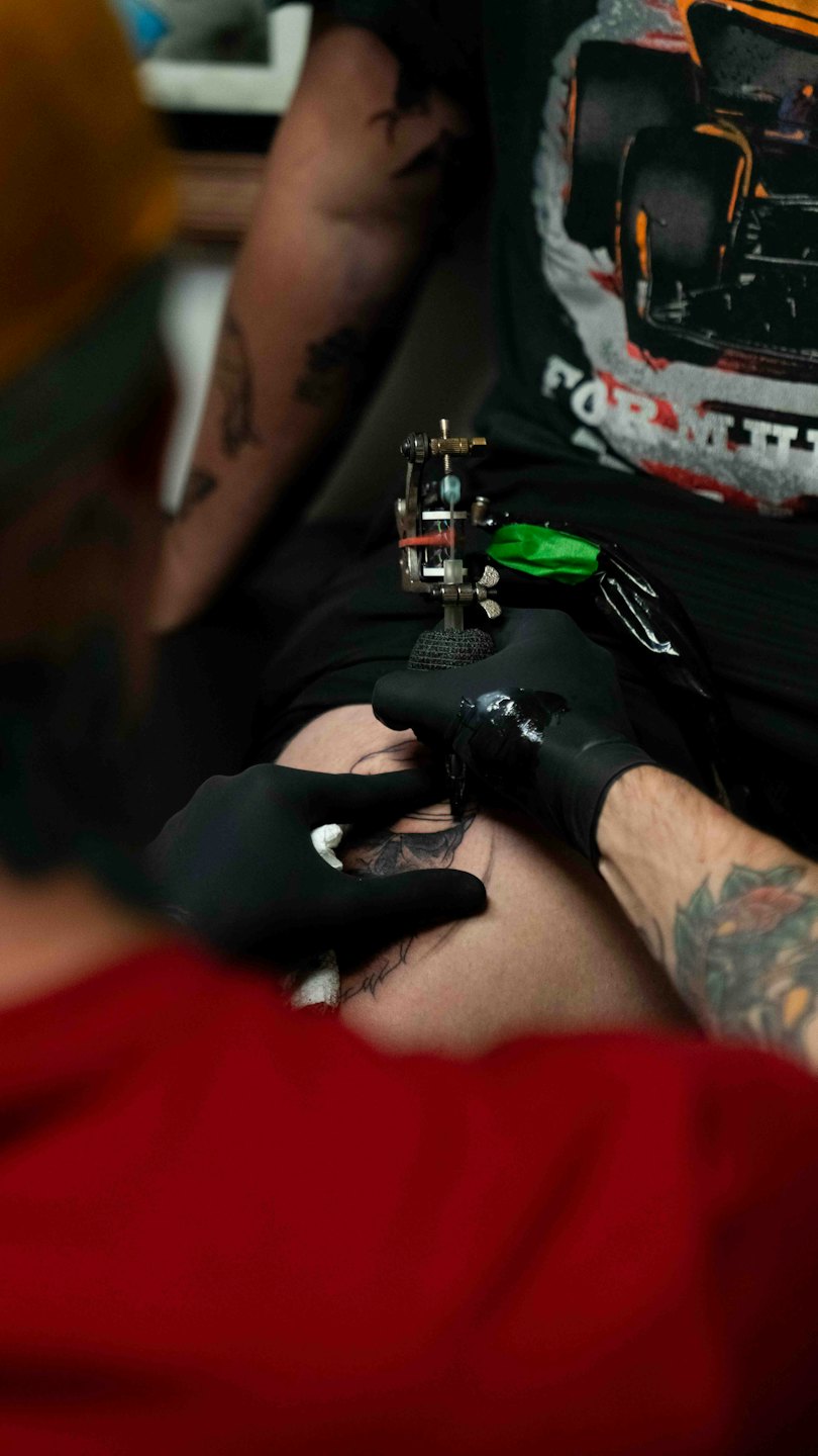 Un tatuatore tatua un disegno sul braccio di un cliente.