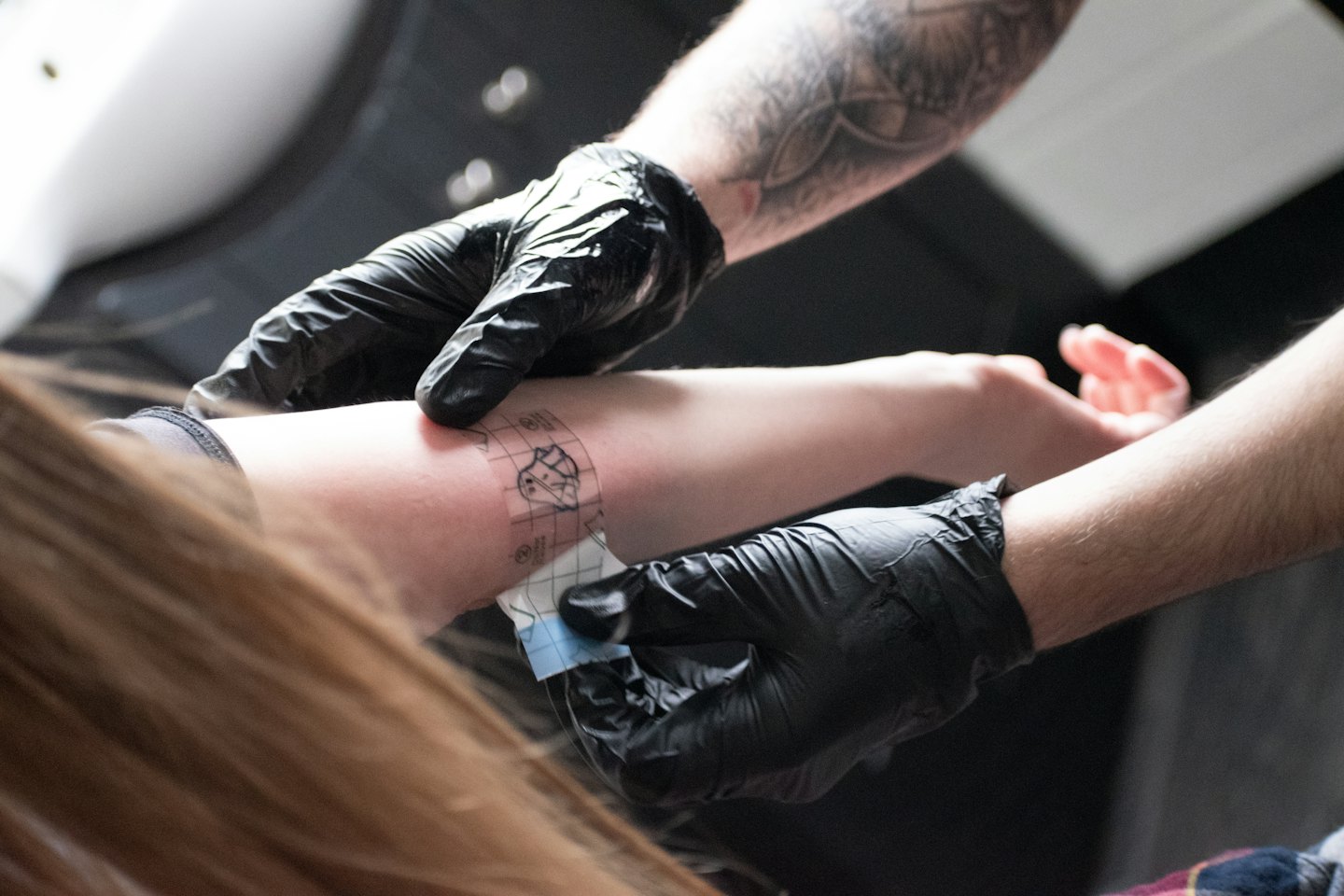 Un tatuatore applica uno stencil sull'avambraccio di un cliente.